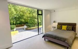 floor to ceiling fixed window with a top hung casement window used to create a glass wall that lets natural light into this bedroom.jpg