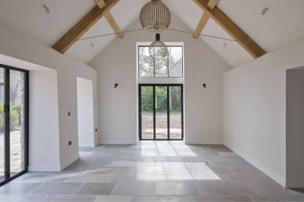 big and bright living room with a tall peaked ceiling natural wooden beams and multiple slim framed aluminium bifold doors