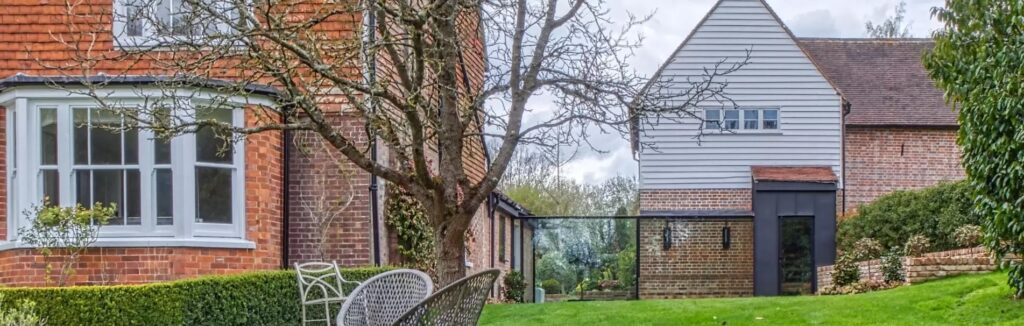 frameless glass link connecting two home buildings to create one large luxury home