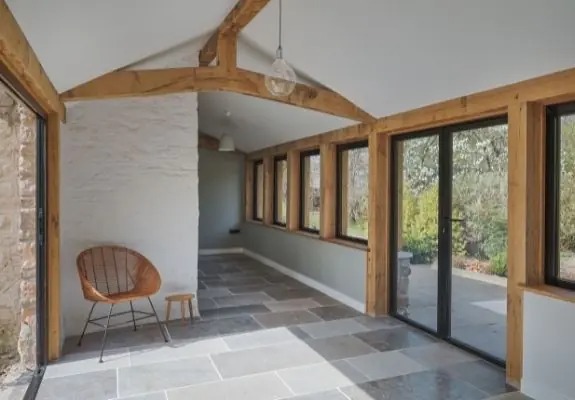 traditional interior design with natural wood means and grey tiled floor with a modern touch from slim framed aluminium windows and doors